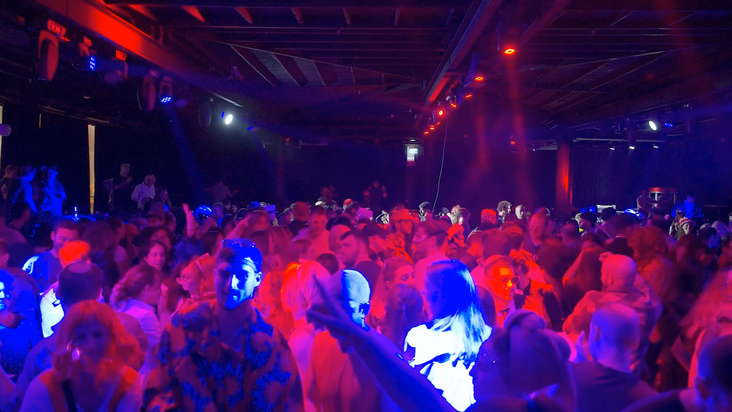 A packed Purim dance floor under red and blue club lights at 126 Ben Yehuda
