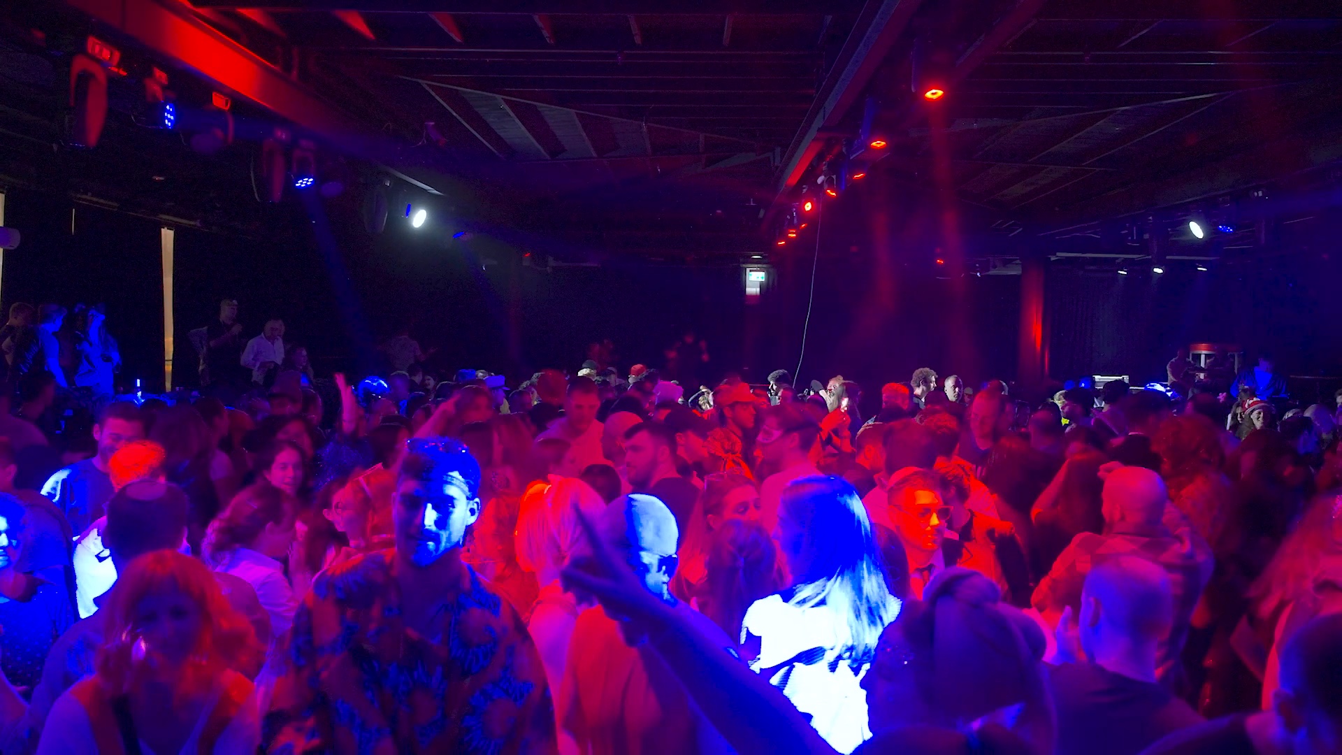 A packed Purim dance floor under red and blue club lights at 126 Ben Yehuda